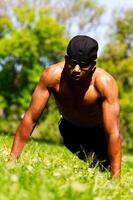 Young African American Man Doing Pushups In Park Strong Sunlight photo