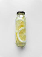 Detox drink with sliced limon in inside glass bottle, isolated on white background. High angle view with copy space. Freshness and hydration concept for health and wellness design. photo