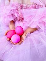 Child in pink tulle dress holding bright pink eggs, Easter celebration concept with a playful and festive feel. For Easter related marketing materials, event invitations, childrens party photo