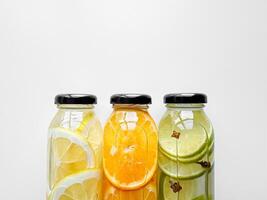 Lemon, orange, and lime detox drinks in glass bottles on white background with copy space. Concept for design and print. photo