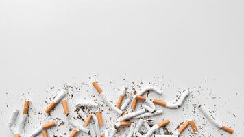 Discarded crushed broken cigarettes and scattered tobacco on white background, representing cessation and the end of smoking with copy space. No tobacco day. photo