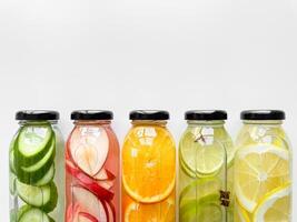 Variety detox drinks in glass bottles on white background, with copy space. Healthy lifestyle and hydration concept for design and print. photo