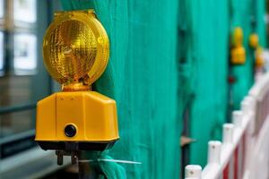 Yellow signal lamp against the background of a green fence. photo