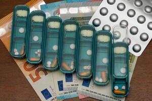 Medical tablets and pills arranged in a case for each day of the week lie on banknotes. photo