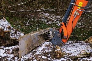 Excavator bucket close-up shoveling about the frozen ground. photo