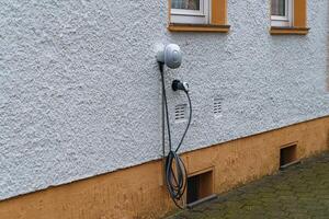 eléctrico coche cargando estación en el pared de un residencial edificio foto