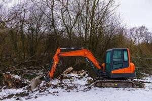 excavador rastrillar el suelo en un cubierto de nieve construcción sitio. foto