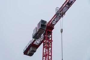 View of a construction crane cabin and part of an arrow against a sky. photo