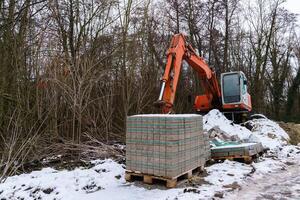 de madera paleta con la carretera losas y excavador en un construcción sitio. foto