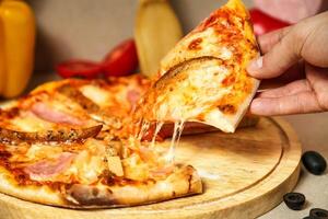 Person Taking a Slice of Pizza photo