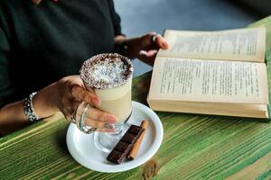 persona sentado a mesa con libro y café foto