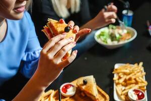 Woman Enjoying a Sandwich and Fries at a Restaurant Table photo