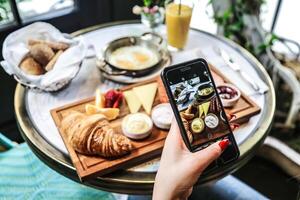 persona tomando imagen de comida en mesa foto