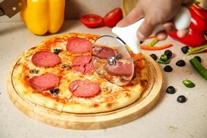 Person Cutting Pizza With Pizza Cutter photo