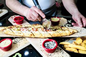 Person Cutting Pizza on Cutting Board photo