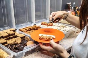 mujer participación plato de comida en frente de buffet foto