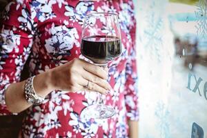 Woman Holding a Glass of Red Wine at a Table Outdoors photo