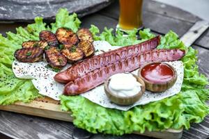 Platter of Sausage, Potatoes, and Lettuce on Wooden Table photo