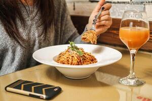 Woman Enjoying Spaghetti With Fork and Glass of Orange Juice photo