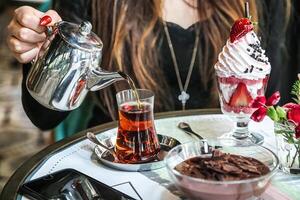 Woman Pours Tea Into Bowl of Ice Cream photo