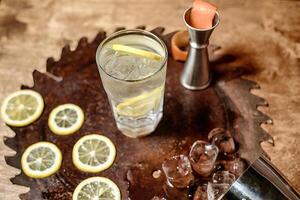 refrescante vaso de agua con rebanado limones en un bandeja foto