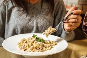 Woman Enjoying a Plate of Pasta With a Glass of Wine photo