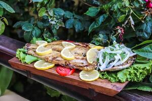 Wooden Cutting Board With Fish, Lettuce, and Lemon Slices photo