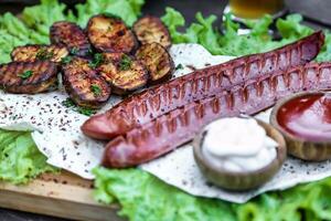 Platter of Grilled Sausages, Potatoes, and Sauces photo