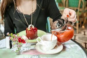 Woman Pouring Tea From Teapot Into Cup photo