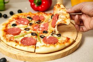 Person Cutting a Slice of Pizza With a Pizza Cutter photo