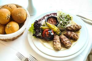 blanco plato con carne y vegetales siguiente a cesta de bollos foto