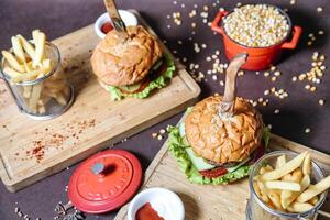 dos hamburguesas y francés papas fritas en un corte tablero foto