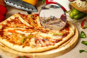 Pizza Cutter Slicing Pizza on Wooden Cutting Board photo