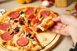 Person Taking a Slice of Pizza at a Restaurant photo