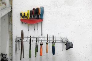 Screwdrivers and other tools hanging on a wall in a workshop photo