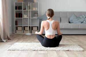 joven mujer practicando yoga a hogar foto