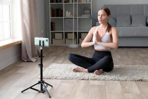 Beautiful young woman in sportswear doing yoga at home. Fitness blogger recording for her blog. photo