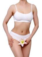 Beautiful slim body of young lady in white underwear. Studio shot. Woman holding a lily flower, isolated photo