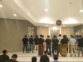 Jakarta, Indonesia - March 23, 2024, A group of moslem people praying shalat in a mosque. View from behind. Islam prayer. photo