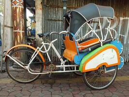 Surakarta, Central Java, Indonesia April 11, 2024. Vintage Becak vehicle is a traditional public transportation from Indonesia. photo