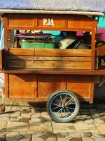 Surakarta City, Central Java, Indonesia. April 11, 2024. An empty homemade wooden stall cart on the street with colorful graffiti art background. Morning ambience to start a selling activity. photo