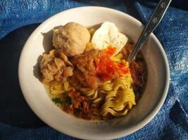 asian culinary delicious noodles soup with meatballs and tofu, served with chili sauce photo