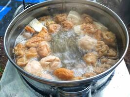 cooking process meatballs and tofu in a boiled broth ready to serve photo