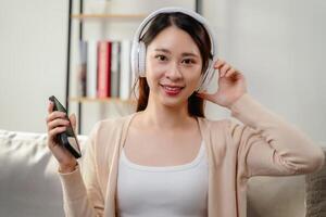 A woman is sitting on a couch with a cell phone in her hand photo