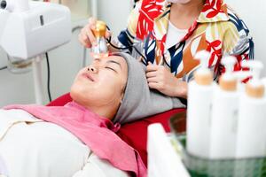 Beauticians perform ultrasound facial procedures with equipment. Woman getting facial massage. photo