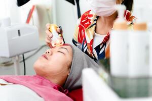 Beauticians perform ultrasound facial procedures with equipment. Woman getting facial massage. photo