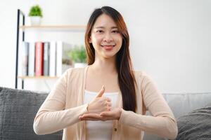 A young deaf woman is sitting on a couch and making a sign Language to communicate. photo