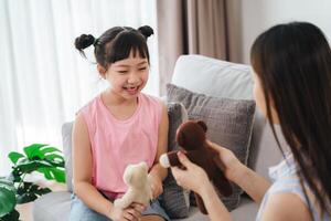 A young girl is sitting on a couch with a stuffed animal in her lap photo