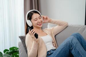 A woman is sitting on a couch with a cell phone in her hand photo