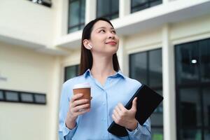 A business woman is standing in the city with a cup of coffee and a tablet photo